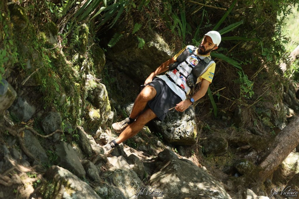 Coureur à casquette blanche dans un passage rocheux en sous-bois
