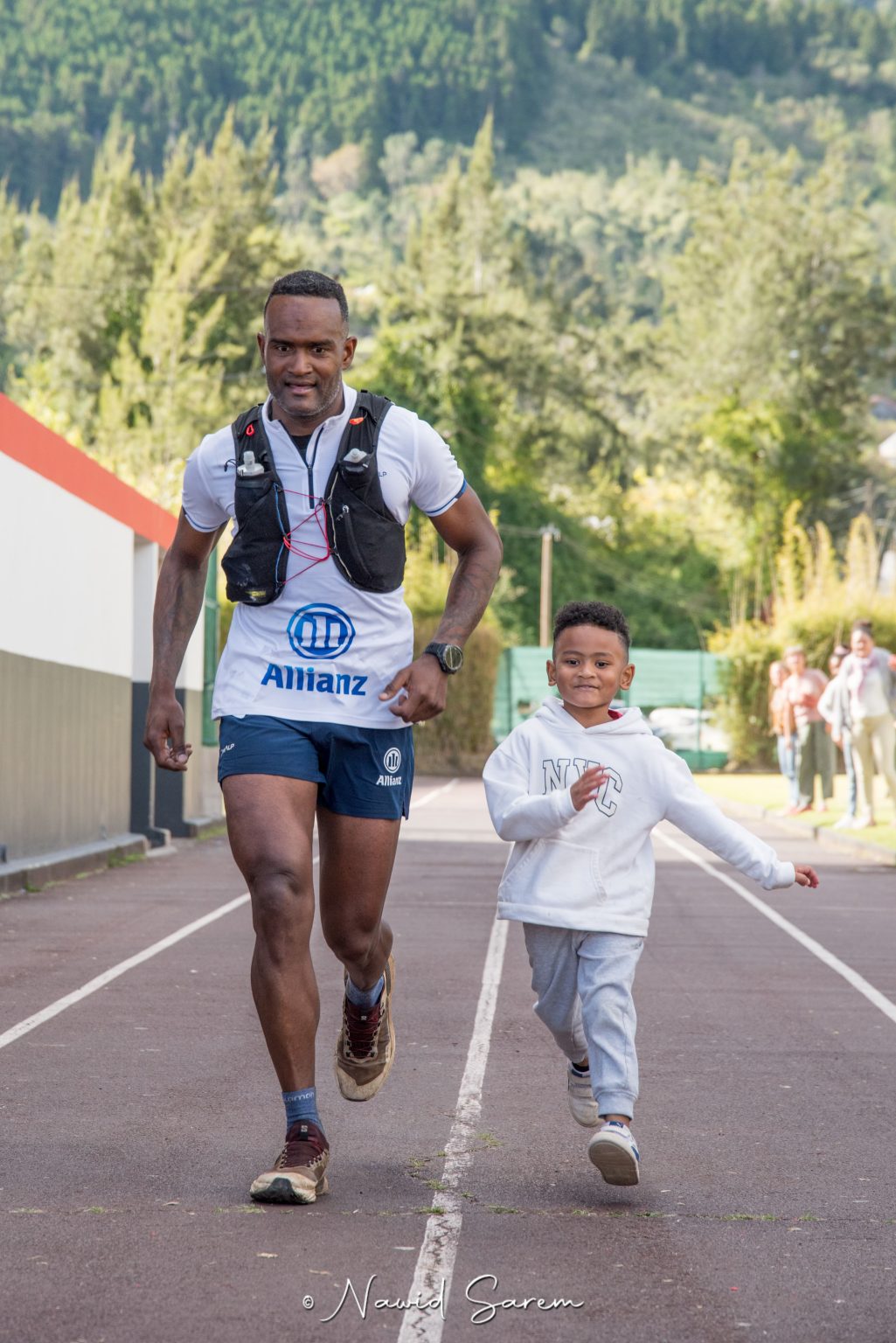 Coureur sur la piste du stade, accompagné d’un enfant, pour les derniers mètres